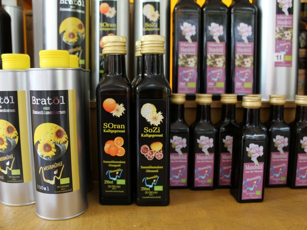 Essig und Öl Verschiedene Flaschen mit hochwertigen Essigen und Ölen auf einem Holzregal, bunt etikettiert.