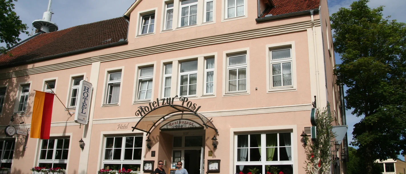 Hotel building with a pink façade and white-framed windows, in front of which bicycles are parked.