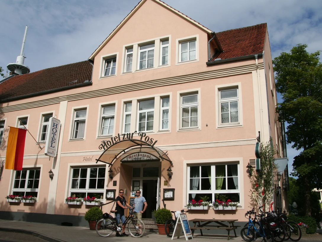 Hotel u. Restaurant zur Post Hotelgebäude mit rosafarbener Fassade und weiß umrahmten Fenstern, vor dem Fahrräder stehen.Hotel building with a pink façade and white-framed windows, in front of which bicycles are parked.Hotelbygning med pinkfarvet facade og hvidindrammede vinduer, foran hvilken der er parkeret cykler.Hotelgebouw met roze gevel en witomrande ramen, waarvoor fietsen worden geparkeerd.