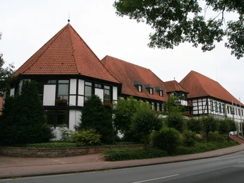 Rehburgs Rathaus mit markantem Fachwerk und roten Ziegeldächern, eingebettet in grüne Bäume.