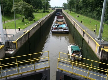 Blick von oben auf die Schleuse Landesbergen mit zwei Booten: ein Frachter und ein kleineres Boot.