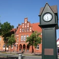 Normaluhr Stolzenau Historische Uhr in Stolzenau vor roten Backsteinfassaden an einem sonnigen Tag mit klarem Himmel.
