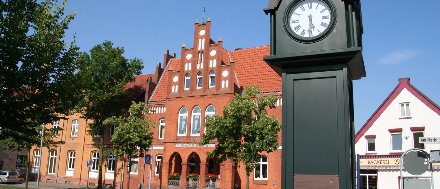 Normaluhr Stolzenau Historische Uhr in Stolzenau vor roten Backsteinfassaden an einem sonnigen Tag mit klarem Himmel.