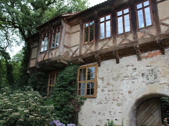 Rittergut Brokeloh Fachwerkgebäude des Ritterguts Brokeloh mit Efeu. Steinwand mit Wappen, Holztüren und Sprossenfenster im Grünen.