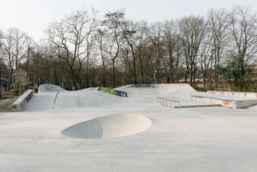 Salatschüssel-Skatepark Weitläufiger Skatepark mit Rampen, Rails und Bowl vor kahlen Bäumen im Hintergrund