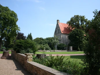 Burg Schlüsselburg Schlossartige Burganlage mit rotem Dach und Türmen, umgeben von üppigem Grün und Gartenanlagen.