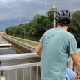 Schleuse Schlüsselburg Ein Radfahrer beobachtet von einer Brücke aus ein vorbeifahrendes Schiff in der Schleuse Schlüsselburg.