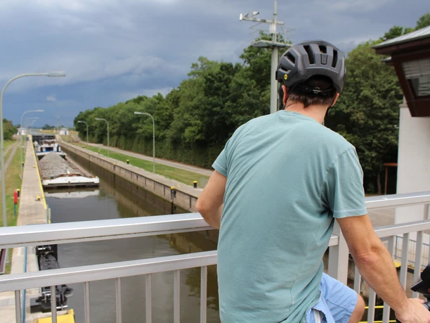 Schleuse Schlüsselburg Ein Radfahrer beobachtet von einer Brücke aus ein vorbeifahrendes Schiff in der Schleuse Schlüsselburg.