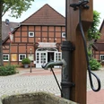 Historisches Fachwerkhaus mit Café im Zentrum von Bruchhausen-Vilsen und alter Wasserpumpe im Vordergrund.