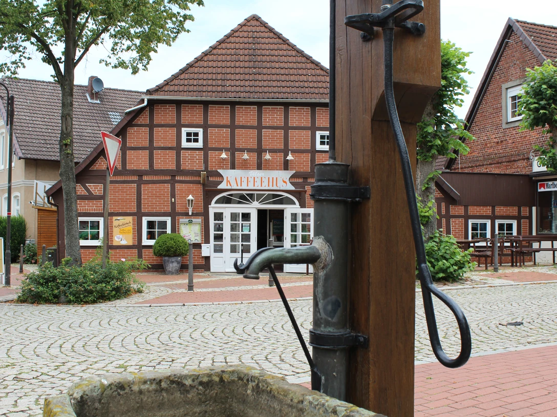 Ortsmitte Bruchhausen-Vilsen Historisches Fachwerkhaus mit Café im Zentrum von Bruchhausen-Vilsen und alter Wasserpumpe im Vordergrund.