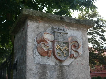 Burg Schlüsselburg Wappen der Burg Schlüsselburg auf einem Mauerpfeiler, umrahmt von grünen Bäumen an einem Sommertag.