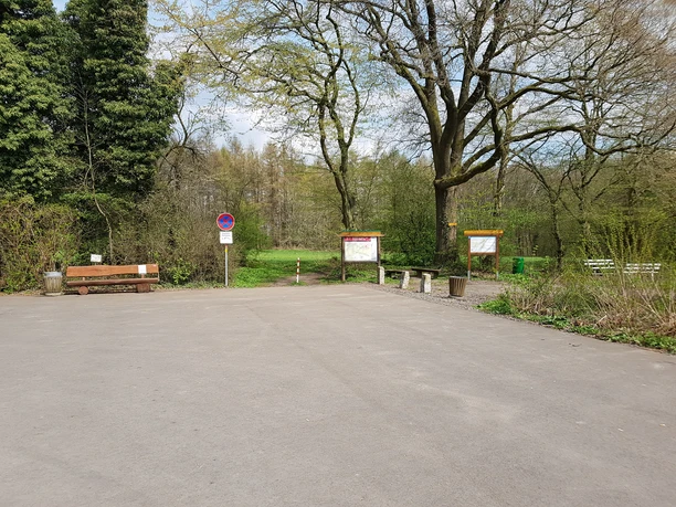 Wanderparkplatz "Schwarzer Brink" Parkplatz mit Bäumen, Informationstafeln und Sitzbänken am Waldrand, ohne Park- und Halteverbotsschild.