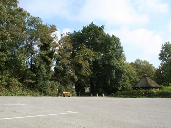 Wanderparkplatz "Schwarzer Brink" Wanderparkplatz mit großzügiger Fläche, umgeben von dichten Bäumen und einem hölzernen Pavillon.