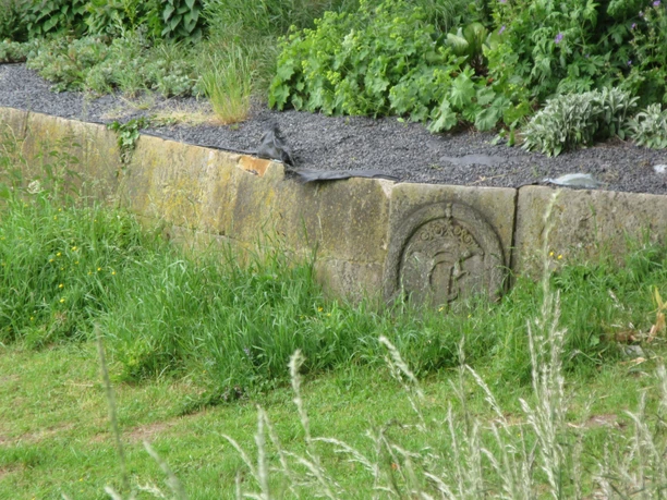 A natural stone wall at the Christian Ludwig Bastion, surrounded by grass and plants, including lavender.