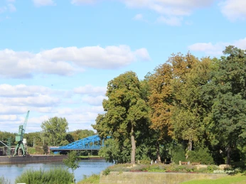Bastion Christian Ludwig Die Bastion Christian Ludwig an einem sonnigen Tag mit Bäumen am Ufer und blauer Brücke im Hintergrund.