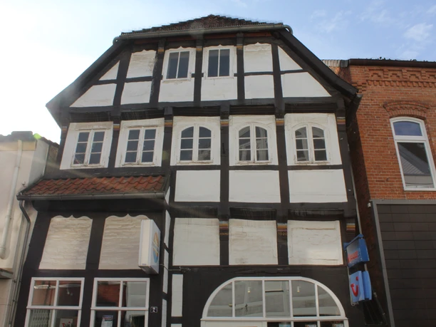 Ackerbürgerhaus Fachwerkhaus mit vier Fenstern, schwarzem Holzrahmen und weißen Wänden, umgeben von Backsteinbauten.