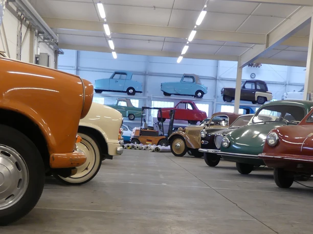 PS.SPEICHER Sammlung KLEINWAGEN von unten Eine Sammlung bunter Kleinwagen in einer Halle. Viele der Oldtimer sind in Regalen gestapelt.