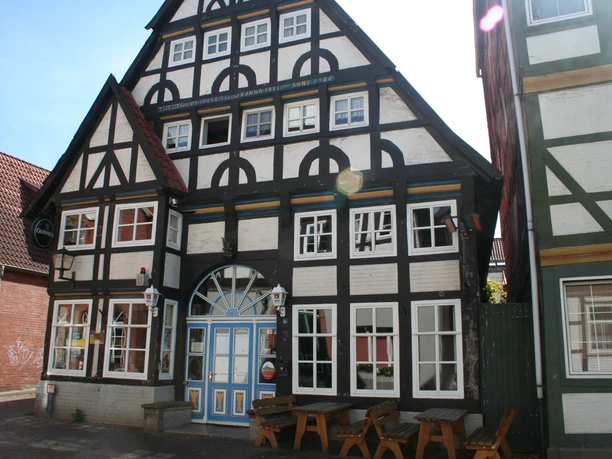 Bürgerhaus Fachwerk-Bürgerhaus mit auffälliger dreieckiger Giebelfront und blauer Tür in historischem Stil.