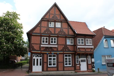 Das Thießensche Haus Fachwerkhaus mit markanten roten Ziegelflächen, angereichert durch weiße Fenster, in einem städtischen Umfeld.
