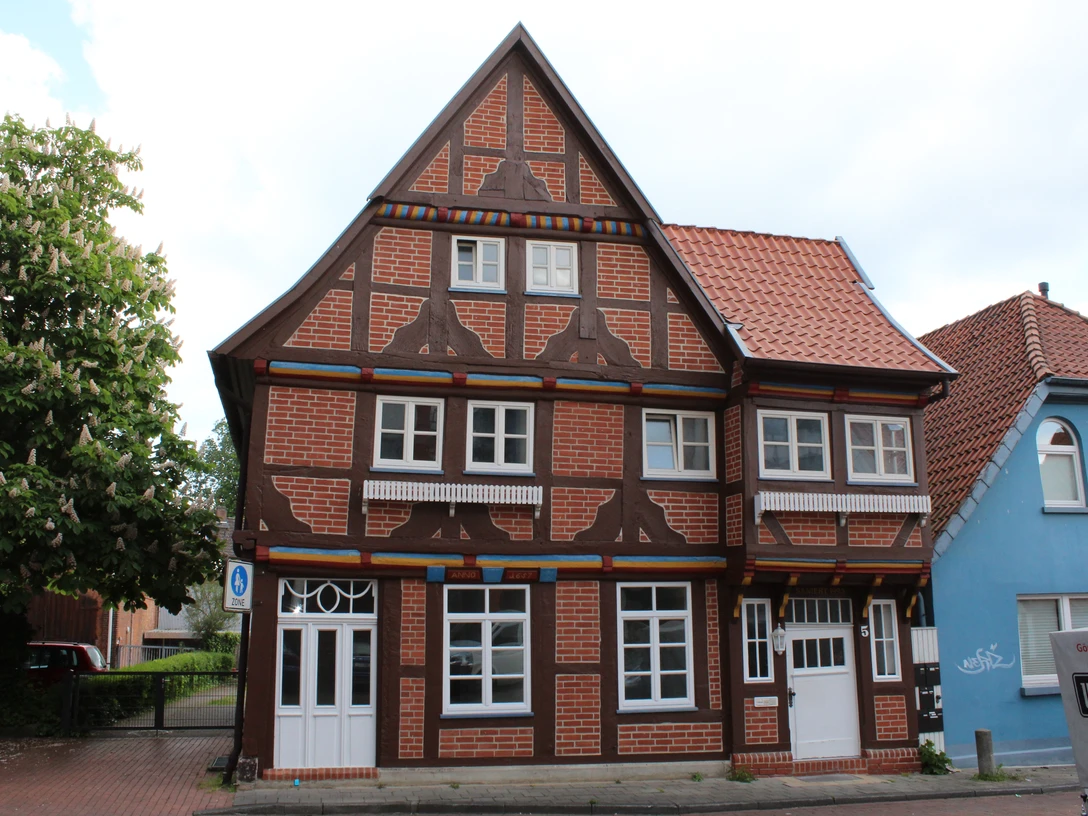 Das Thießensche Haus Fachwerkhaus mit markanten roten Ziegelflächen, angereichert durch weiße Fenster, in einem städtischen Umfeld.