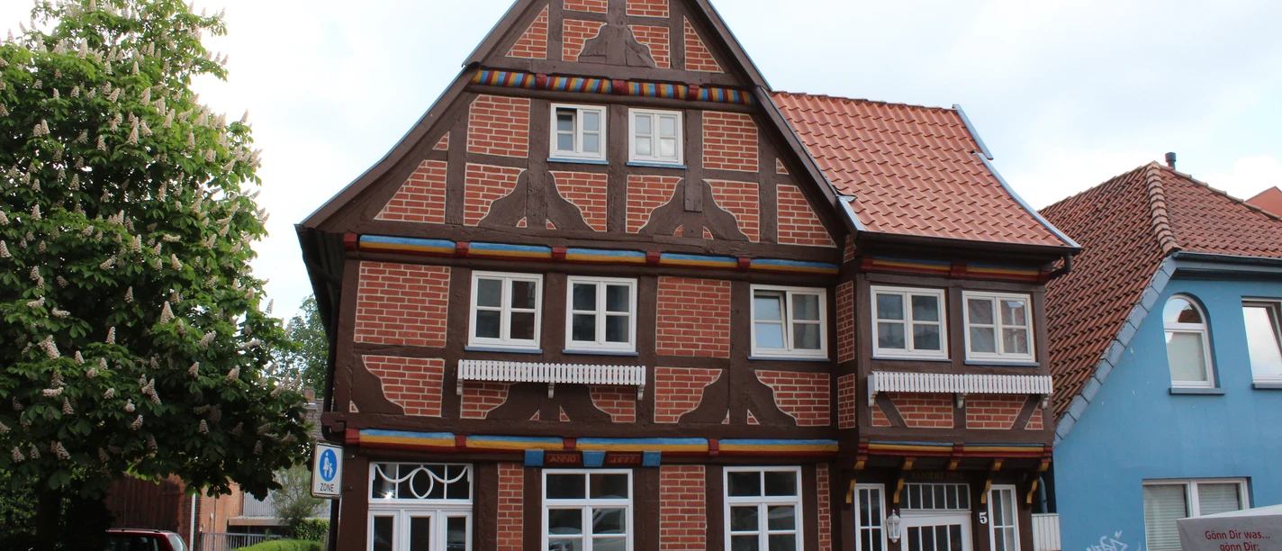 Das Thießensche Haus Fachwerkhaus mit markanten roten Ziegelflächen, angereichert durch weiße Fenster, in einem städtischen Umfeld.
