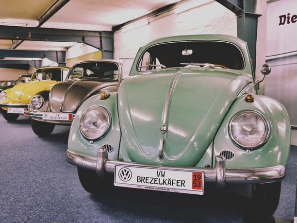 Mehrere VW Käfer in der Sammlung AUTOMOBIL, vorne ein grüner Brezelkäfer.
