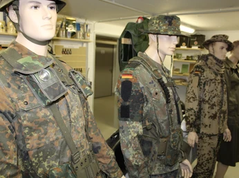 Ausstellung von Militäruniformen mit verschiedenen Tarnmustern und originalen Ausrüstungsgegenständen.