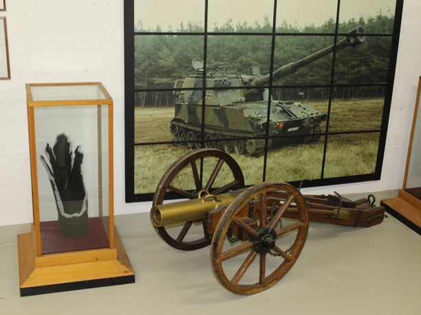 Eine alte Kanone und moderne Panzerartillerie in einer militärhistorischen Ausstellung.