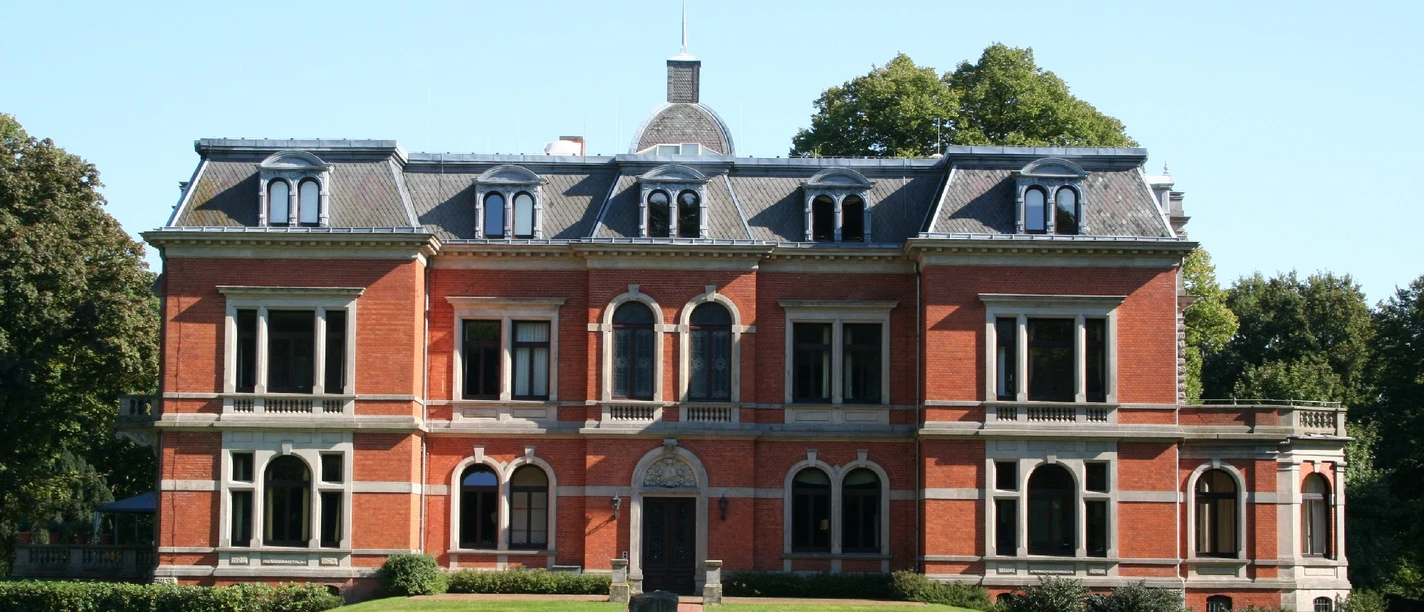 Schloß Etelsen Historisch wirkendes Backsteinschloss Etelsen mit zinnenverziertem Dach, umgeben von Grünflächen.