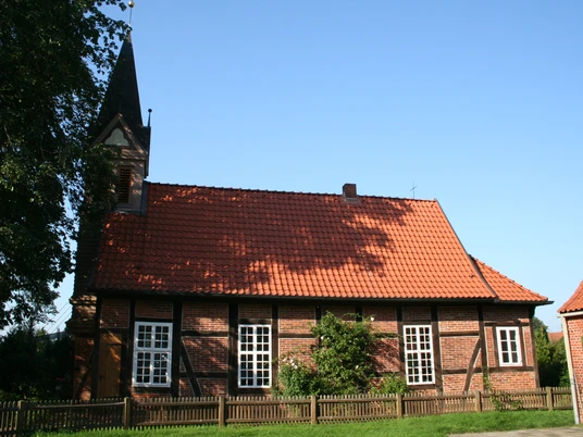 Fachwerkkapelle Anderten Fachwerkkapelle in Anderten mit rotem Ziegeldach und umgebender Holzzaun vor blauem Himmel.