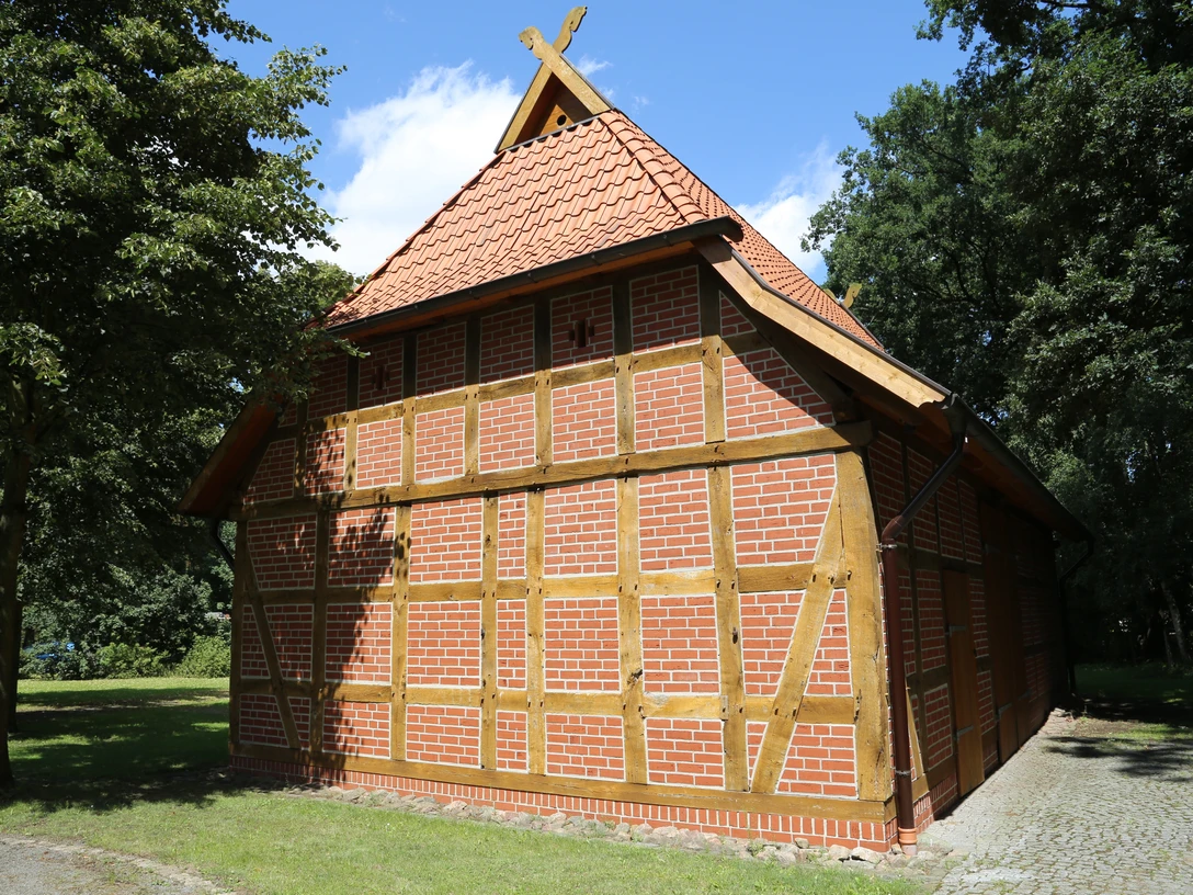 Rövers Schafstall Ein traditionelles Fachwerkgebäude mit rotem Ziegeldach im Grünen bei sonnigem Wetter.