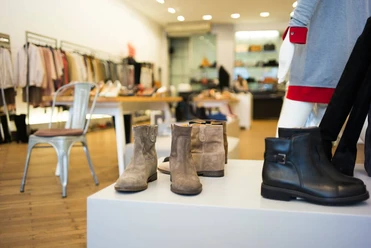 PREGO Das Bild zeigt moderne Schuhe und Stiefel in einer stilvollen Boutique auf hölzernem Boden präsentiert.