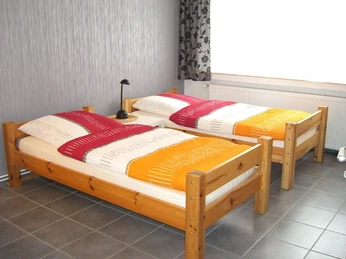 Zwei Einzelbetten mit farbenfroher Bettwäsche in einem hellen Raum mit moderner Gestaltung.Two single beds with colorful bedding in a bright room with a modern design.To enkeltsenge med farverigt sengelinned i et lyst værelse med moderne design.Twee eenpersoonsbedden met kleurrijk beddengoed in een lichte kamer met een modern ontwerp.