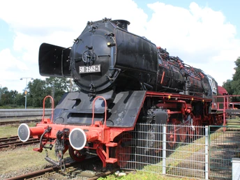 Lok Weyhe Eine historische Dampflok steht majestätisch auf Gleisen, eingerahmt von einem grünen Zaun.