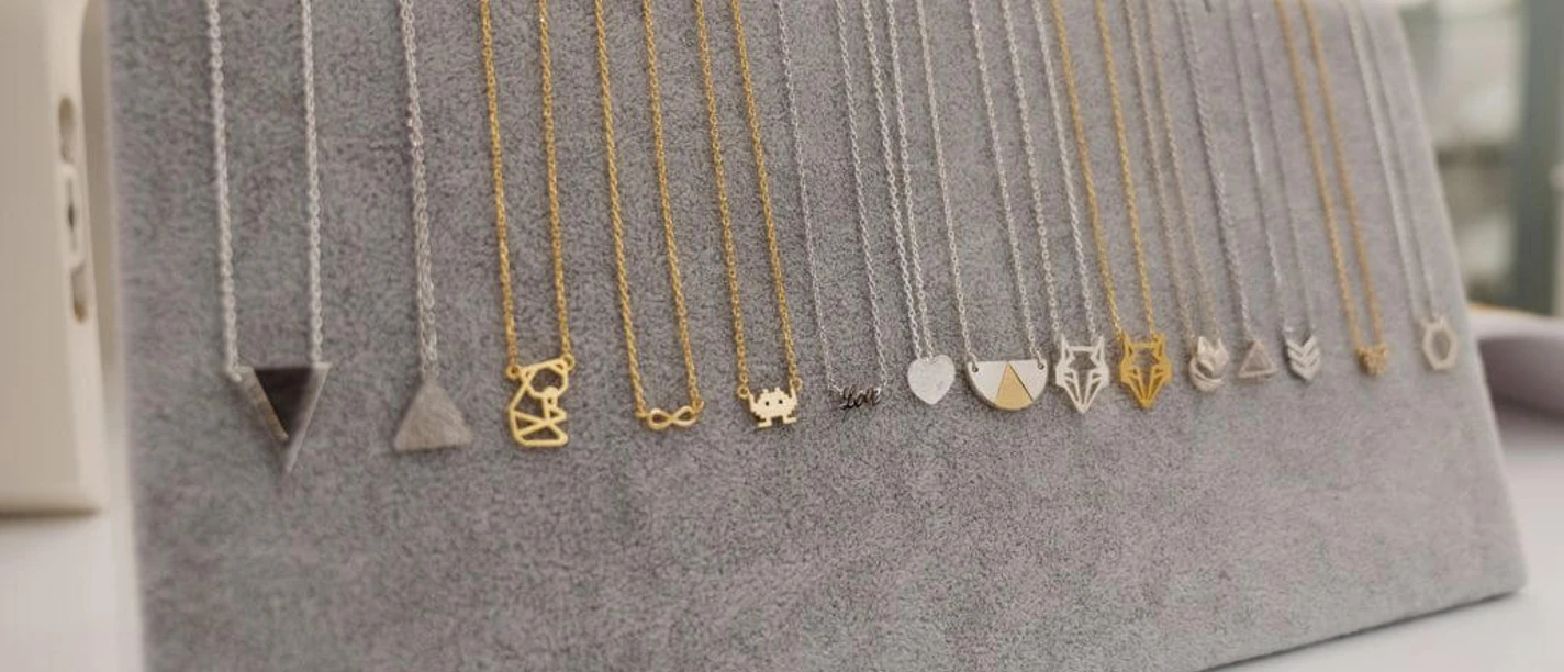 APRICOT room A selection of delicate necklaces with different pendants hangs on a gray display area.
