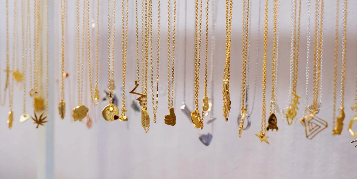 Santa Rosa Verschiedene goldfarbene und silberne Ketten mit diversen Anhängern hängen nebeneinander in einer Reihe.Various gold-colored and silver chains with different pendants hang next to each other in a row.