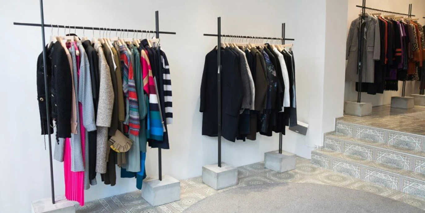 MATA Cologne Innenansicht eines Modegeschäfts mit bunten und neutralen Kleidungsstücken auf Kleiderstangen.Interior view of a fashion store with colorful and neutral garments on clothes rails.