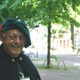 Ein älterer Mann in historischer Kleidung lächelt bei sonnigem Wetter in einem Park in Nienburg.