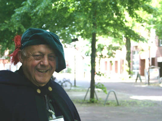 Ein älterer Mann in historischer Kleidung lächelt bei sonnigem Wetter in einem Park in Nienburg.