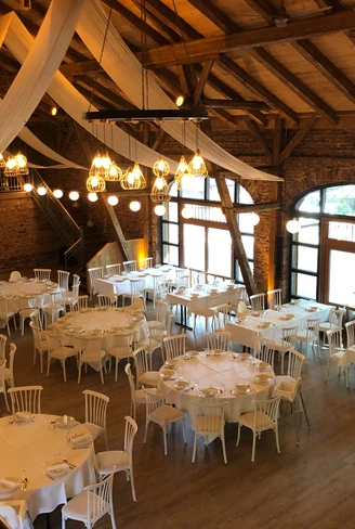 Großer, eleganter Festsaal mit Holzbalken, runden und rechteckigen Tischen und dezentem Licht.Large, elegant ballroom with wooden beams, round and rectangular tables and subtle lighting.Stor, elegant balsal med træbjælker, runde og rektangulære borde og afdæmpet belysning.Grote, elegante balzaal met houten balken, ronde en rechthoekige tafels en subtiele verlichting.