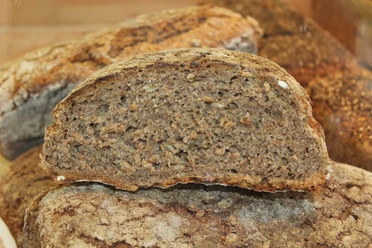 Brot Dunkles, körniges Vollkornbrot mit knuspriger Kruste in der Nahaufnahme, erkennbar Körner im Inneren.
