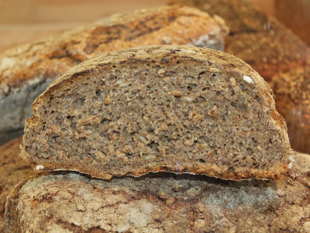 Brot Dunkles, körniges Vollkornbrot mit knuspriger Kruste in der Nahaufnahme, erkennbar Körner im Inneren.