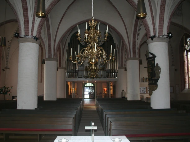 Interior view of St. Martin's Church in Nienburg with impressive chandelier and vaulted ceilings.