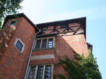 Backsteinfassade des Stockturms in Nienburg mit Efeubewuchs, Fachwerkgiebel und blauen Himmel.