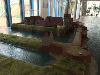 Ein detailliertes Modell eines historischen Schlosses auf einer Insel, umgeben von Wasser und Vegetation.