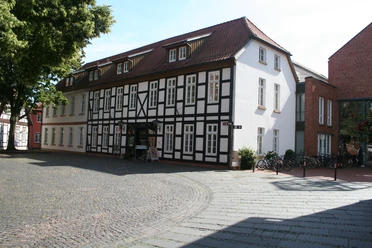 Fachwerkhaus in Nienburg mit rotem Satteldach und Kopfsteinpflaster im Vordergrund.