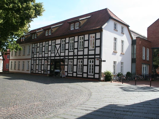Fachwerkhaus in Nienburg mit rotem Satteldach und Kopfsteinpflaster im Vordergrund.
