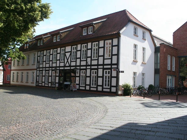 Fachwerkhaus in Nienburg mit rotem Satteldach und Kopfsteinpflaster im Vordergrund.