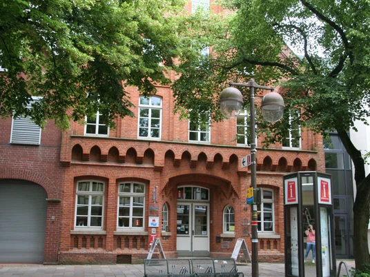 Tourist-Information Nienburg Historisches Backsteingebäude in Nienburg mit Tourist-Information unter Bäumen und umliegenden Geschäften.Historic brick building in Nienburg with tourist information office under trees and surrounding stores.Historisk murstensbygning i Nienburg med turistinformation under træer og omkringliggende butikker.Historisch bakstenen gebouw in Nienburg met toeristeninformatiecentrum onder bomen en omliggende winkels.