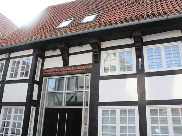 Traufenhaus Weserstraße Nienburg Fachwerkgebäude mit rotem Ziegeldach in Nienburg, über dem Eingang ein historisches Schild.
